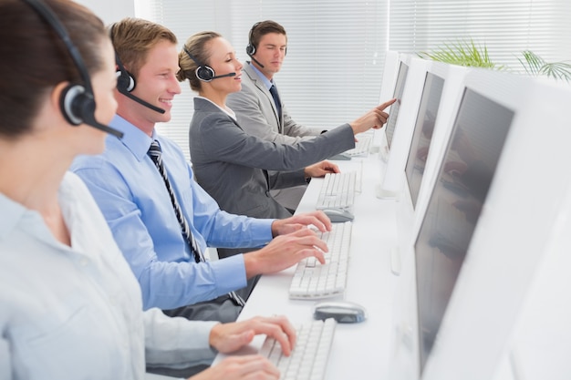 Business team working on computers and wearing headsets