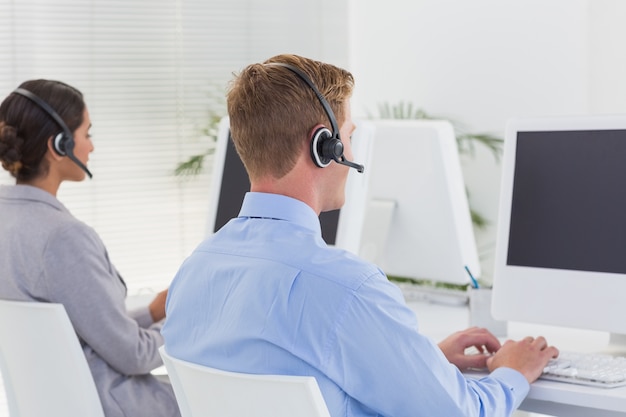 Business team working on computers and wearing headsets