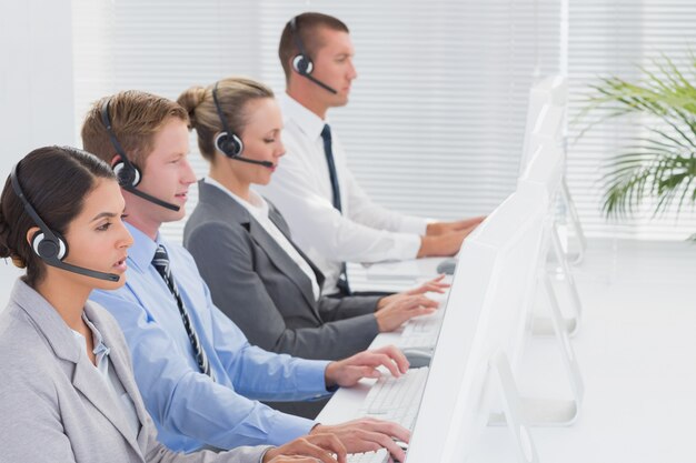 Business team working on computers and wearing headsets