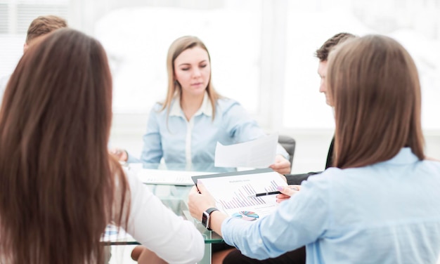 Il team aziendale a una conferenza di lavoro seduto a una scrivania e discutendo questioni importanti