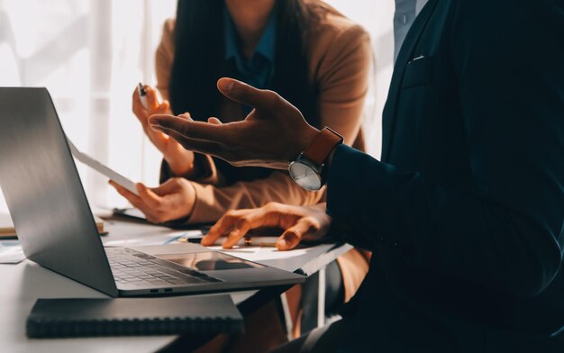 Foto team aziendale che lavora con un nuovo progetto di startup e discute informazioni per la strategia finanziaria con laptop e tablet digitali in una moderna sala business