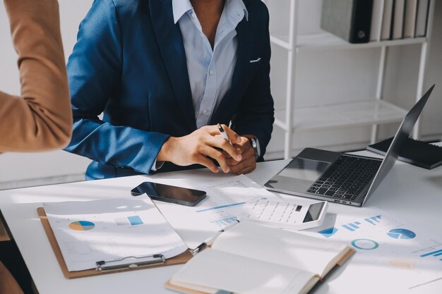 Foto team aziendale che lavora con un nuovo progetto di startup e discute informazioni per la strategia finanziaria con laptop e tablet digitali in una moderna sala business