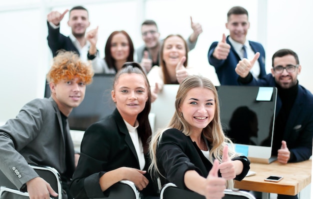 Business team zit aan een bureau en duimen opdagen