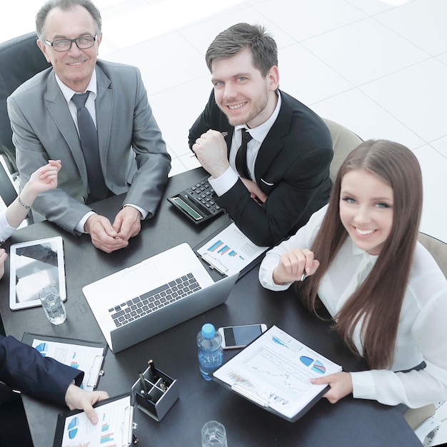 Business team zit aan een bureau en kijkt naar de camera