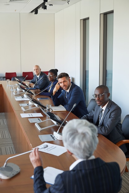 Business team zittend aan tafel en luisteren naar zakenvrouw op conferentie