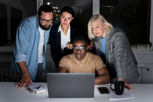 Foto compagni di squadra di lavoro che lavorano fino a tardi in ufficio