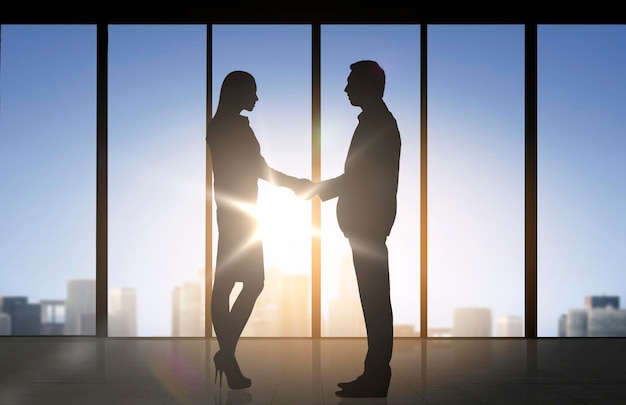 business, teamwork, partnership, cooperation and people concept - business people shaking hands over office background