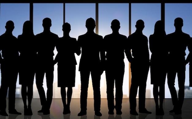 business, teamwork and people concept - business people silhouettes over office background