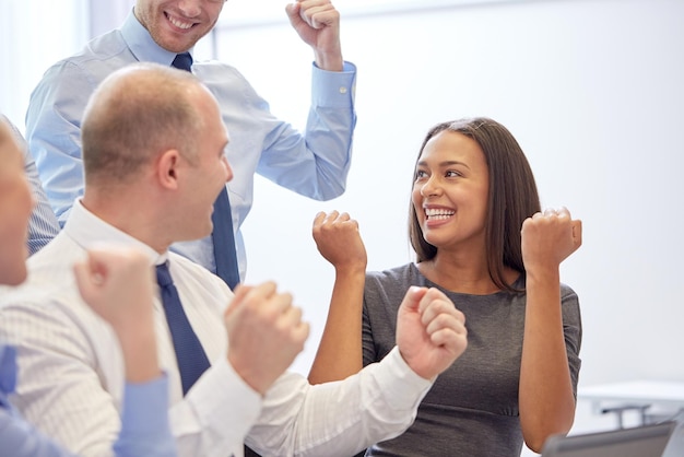 Photo business, teamwork, people and success concept - smiling business team making triumph gesture in office