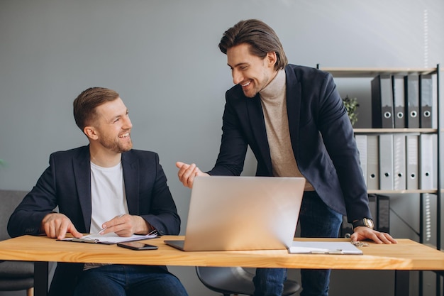 Business teamwork two smiling corporate businessmen working together on laptop