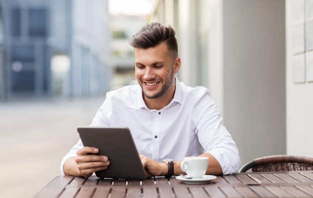 business, technologie en mensen concept - jonge man met tablet pc-computer en koffiekopje op city street café