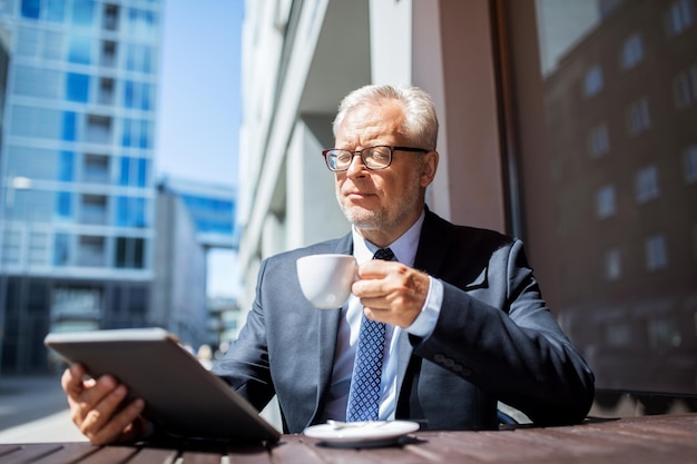 business, technologie en mensen concept - senior zakenman met tablet pc-computer die koffie drinkt in het café in de stad