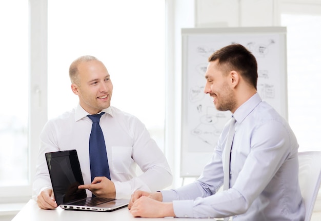 business, technologie en office concept - twee lachende zakenlieden met laptop met presentatie in office