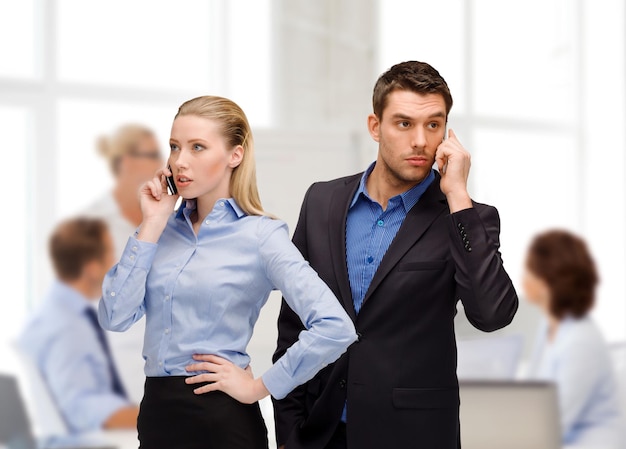 business, technology, communication concept - businesswoman and businessman with cell phones calling