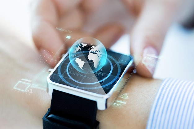 business, technology, communication, connection and people concept - close up of woman hands globe hologram on smartwatch