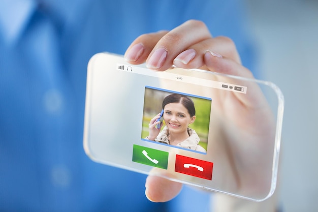 Photo business, technology, communication and people concept - close up of woman hand holding and showing incoming call on transparent smartphone screen