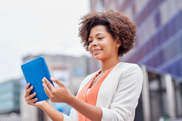 business, technology, communication and people concept - young smiling african american businesswoman with tablet pc computer in city