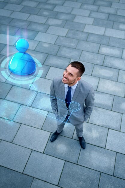 business, technology, connection and people concept - young smiling businessman with virtual screen and user icon outdoors from top