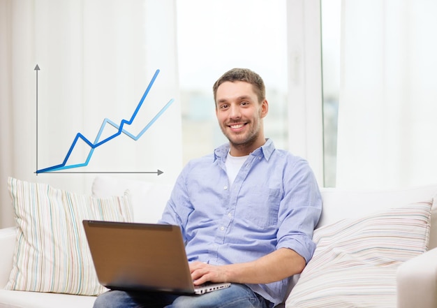 концепция бизнеса, технологий и электронного обучения - улыбающийся мужчина, работающий с ноутбуком дома