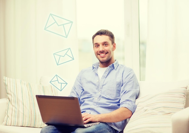 business, technology and e-learning concept - smiling man working with laptop at home