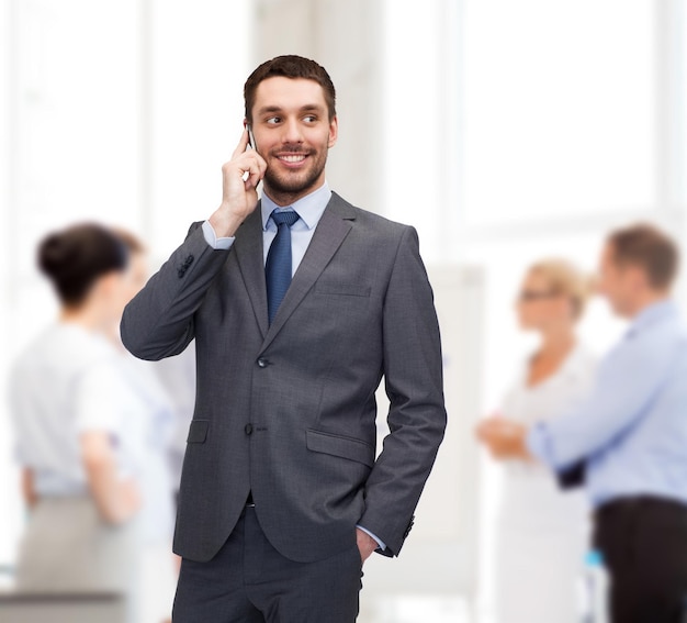 business, technology and education concept - friendly young smiling businessman with smartphone