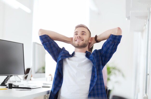 business, technology, education and people concept - happy young creative man or student with computer at office