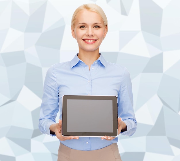 ビジネス、テクノロジー、インターネット、広告のコンセプト – グレーのグラフィック低ポリゴン背景に空白の黒いタブレットPCコンピュータ画面を持つビジネスウーマンの笑顔