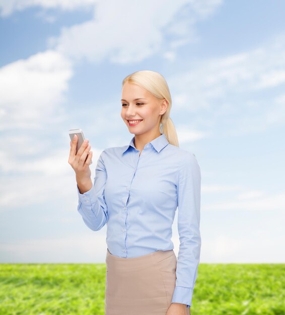 business, technology, internet and education concept - friendly young smiling businesswoman with smartphone