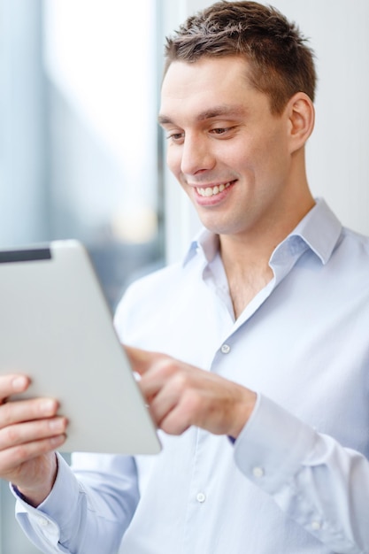 концепция бизнеса, технологий, интернета и офиса - улыбающийся бизнесмен с планшетным компьютером в офисе
