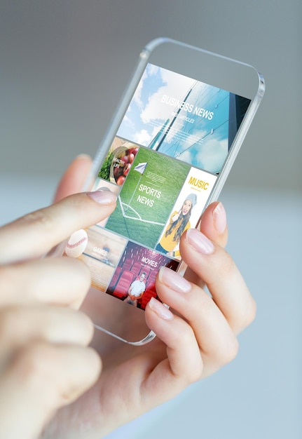 Photo business, technology, internet and people concept - close up of woman hand holding and showing transparent smartphone with news web pages on screen