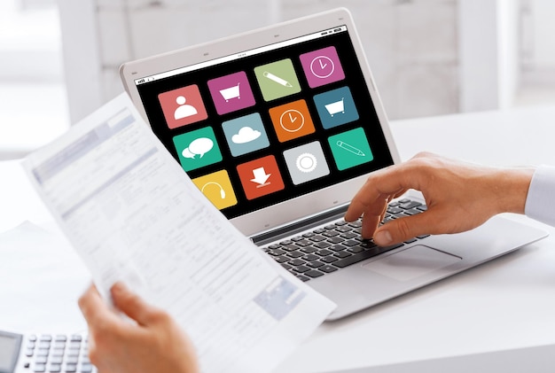 концепция бизнеса, технологий, мультимедиа и людей - бизнесмен с иконками меню на экране ноутбука, работающий в офисе
