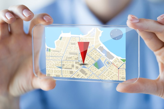 business, technology, navigation, location and people concept - close up of woman hand holding and showing transparent smartphone with gps navigator map on screen at office