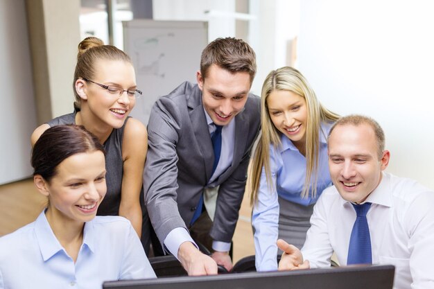 business, technology and office concept - smiling business team with computer monitor having discussion in office