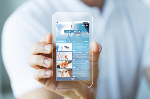 business, technology and people concept - close up of male hand holding and showing transparent smartphone with world news web page on screen