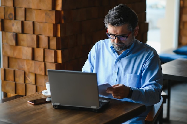 Foto tecnologia aziendale e concetto di persone uomo d'affari senior con computer portatile che beve caffè al caffè moderno