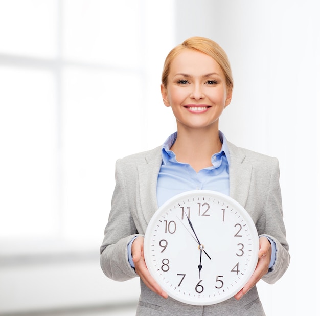 business and time concept - attractive businesswoman with wall clock