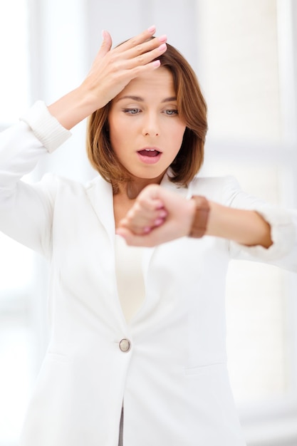 business and time management concept - stressed businesswoman looking at wrist watch in office