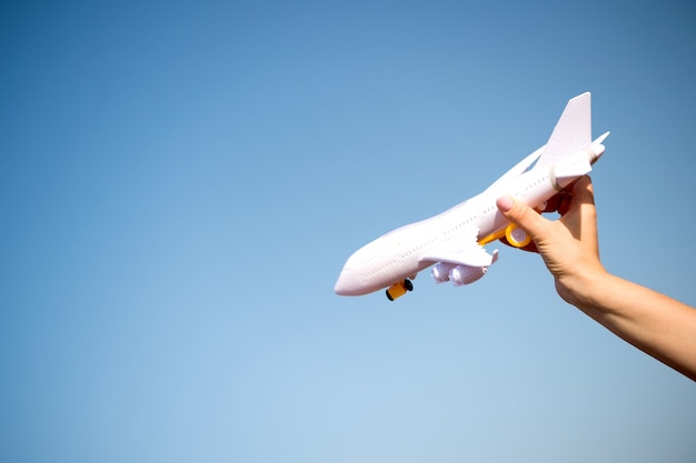 Business traveling and vacation. freedom and inspiration. airmail and postal delivery concept. white toy plane in female hand landing or falling on sunny blue sky background, copy space