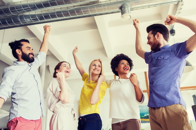 business, triomf, gebaar, mensen en teamwork concept - gelukkig creatief team dat de handen opsteekt en de overwinning op kantoor viert