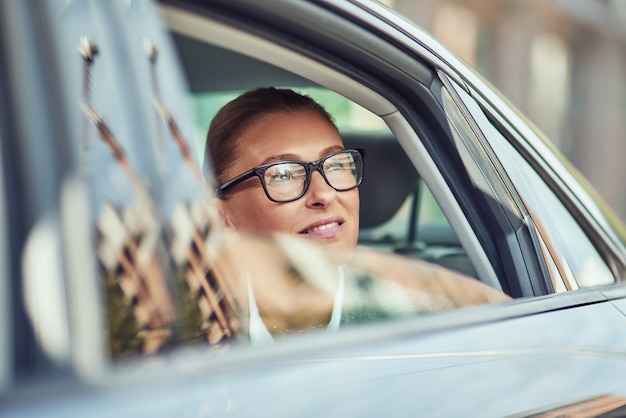 Business trip beautiful middle aged business woman wearing eyeglasses looking out of a car window