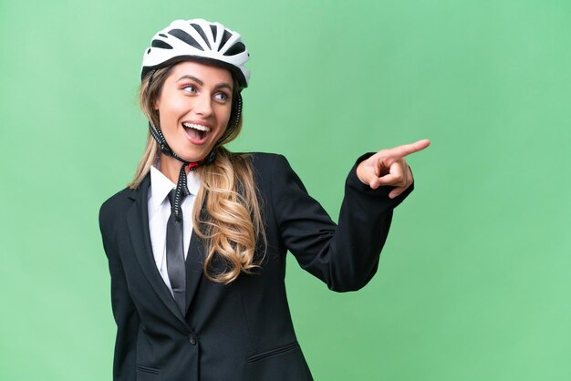孤立した背景にヘルメット バイカーを身に着けているビジネス ウルグアイの女性が指を横に向け、製品を提示する
