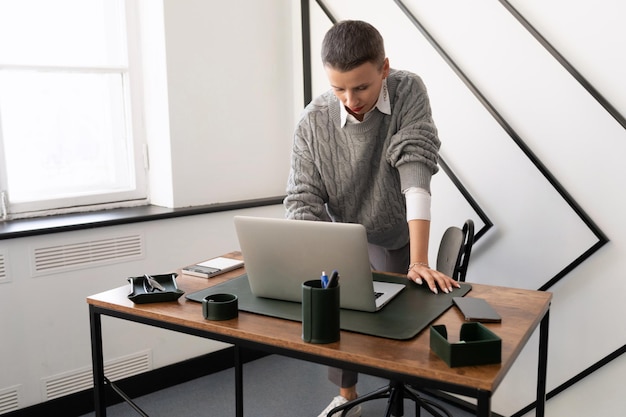 Business woman accountant at the workplace stands and looks\
into the laptop to solve business issues