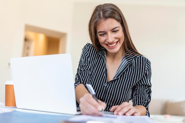 Business woman analyzing data using computer while spending time in the office Beautiful young grinning professional woman in office Graphs and charts