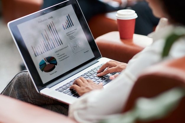 Business woman analyzing financial charts on a laptop