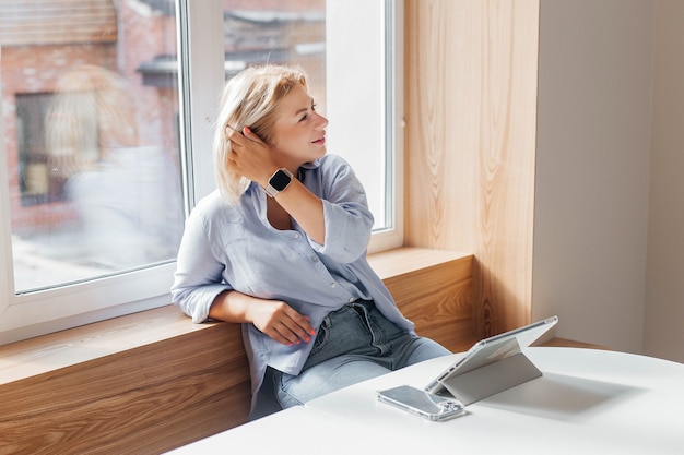 Business woman in a blue shirt working on notebook in a cafe on a white table