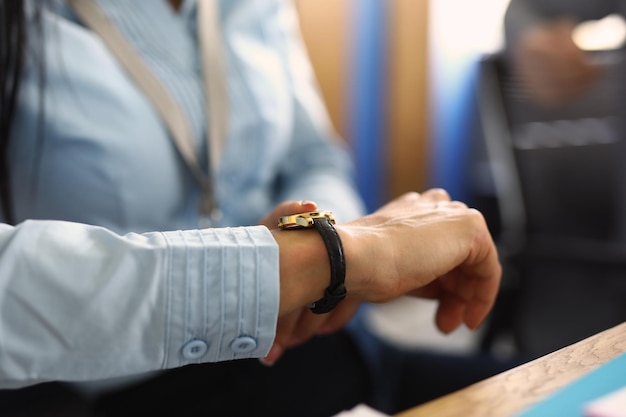 Photo business woman boss checks time on clock in office closeup