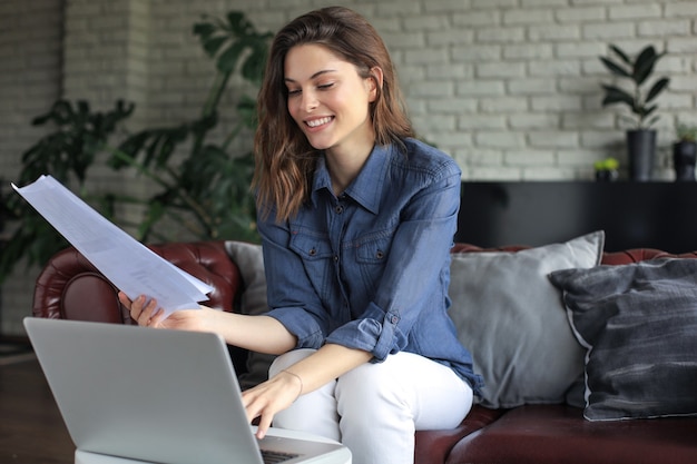business woman checking paper documents in home office,working on laptop from home.