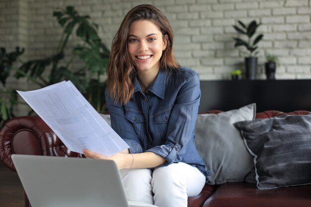 Business woman checking paper documents in home office,working on laptop from home.