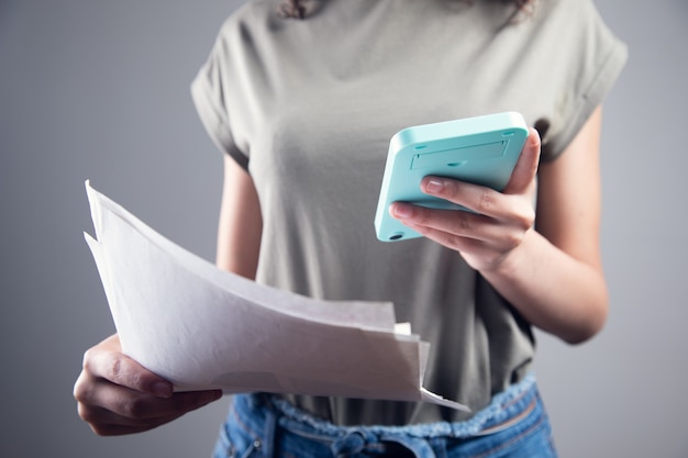 Photo business woman counting on calculator and holding documents in hands