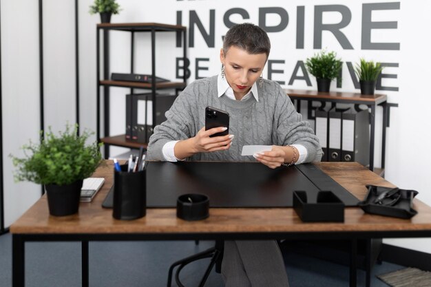 Business woman dialing a number on the phone with a business card in her hands